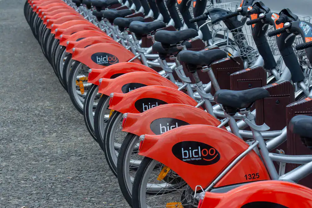 Line of high quality rental bicycles parked securely next to a stone wall