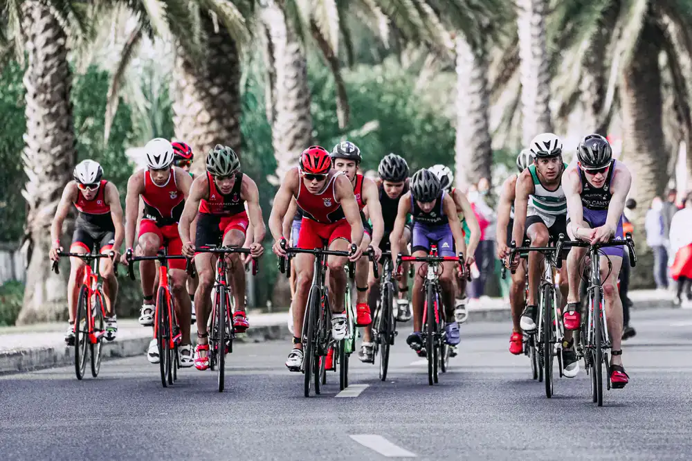 A large group of cyclists riding together through sunlit rolling hills